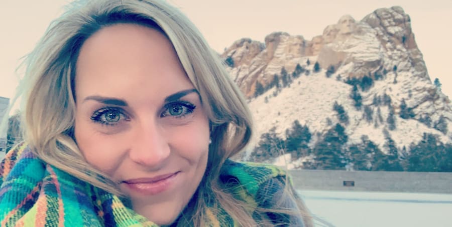 Elisabeth smiling in a colorful scarf in front of a snowy granite mountain